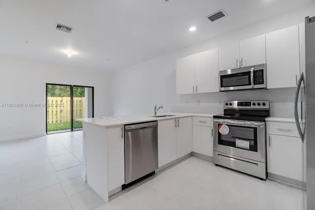 a kitchen with granite countertop white cabinets and stainless steel appliances