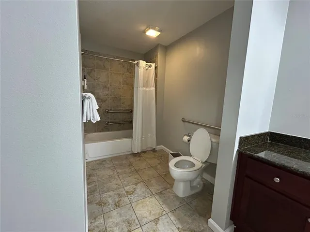 a bathroom with a granite countertop toilet and a shower
