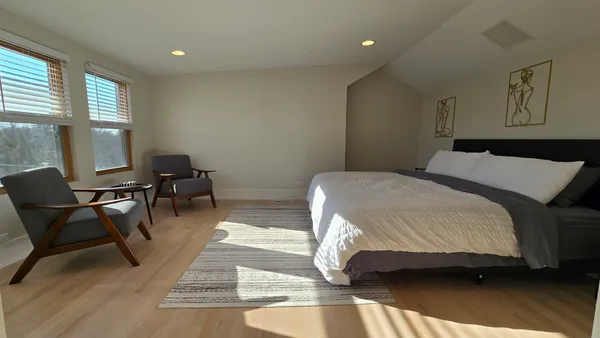 a spacious bedroom with a bed a chair and large windows