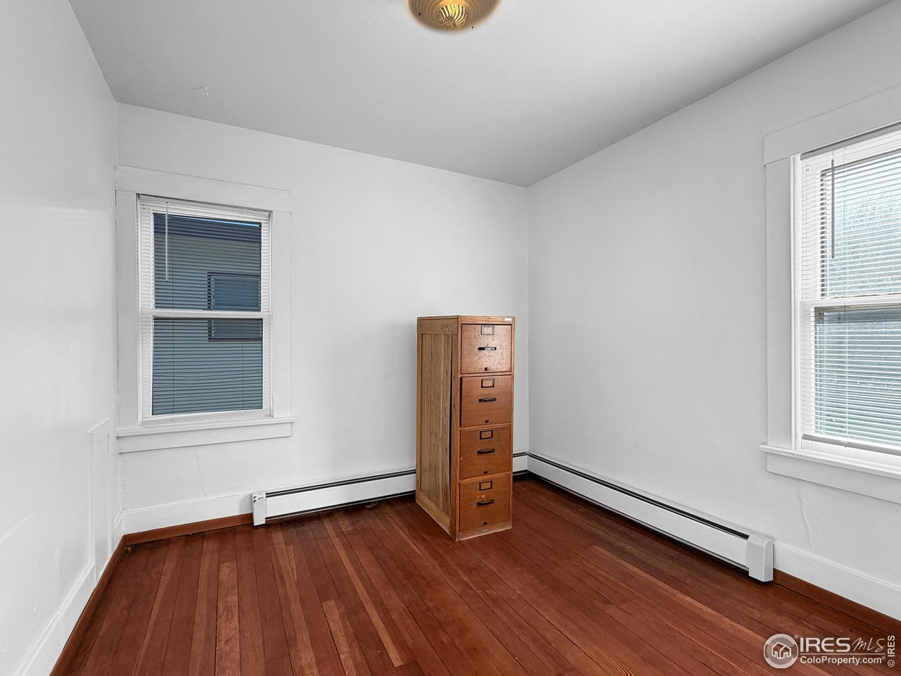 531 Taylor Street Sterling, CO 80751 - Photo 13 of 38 an empty room with wooden floor and windows