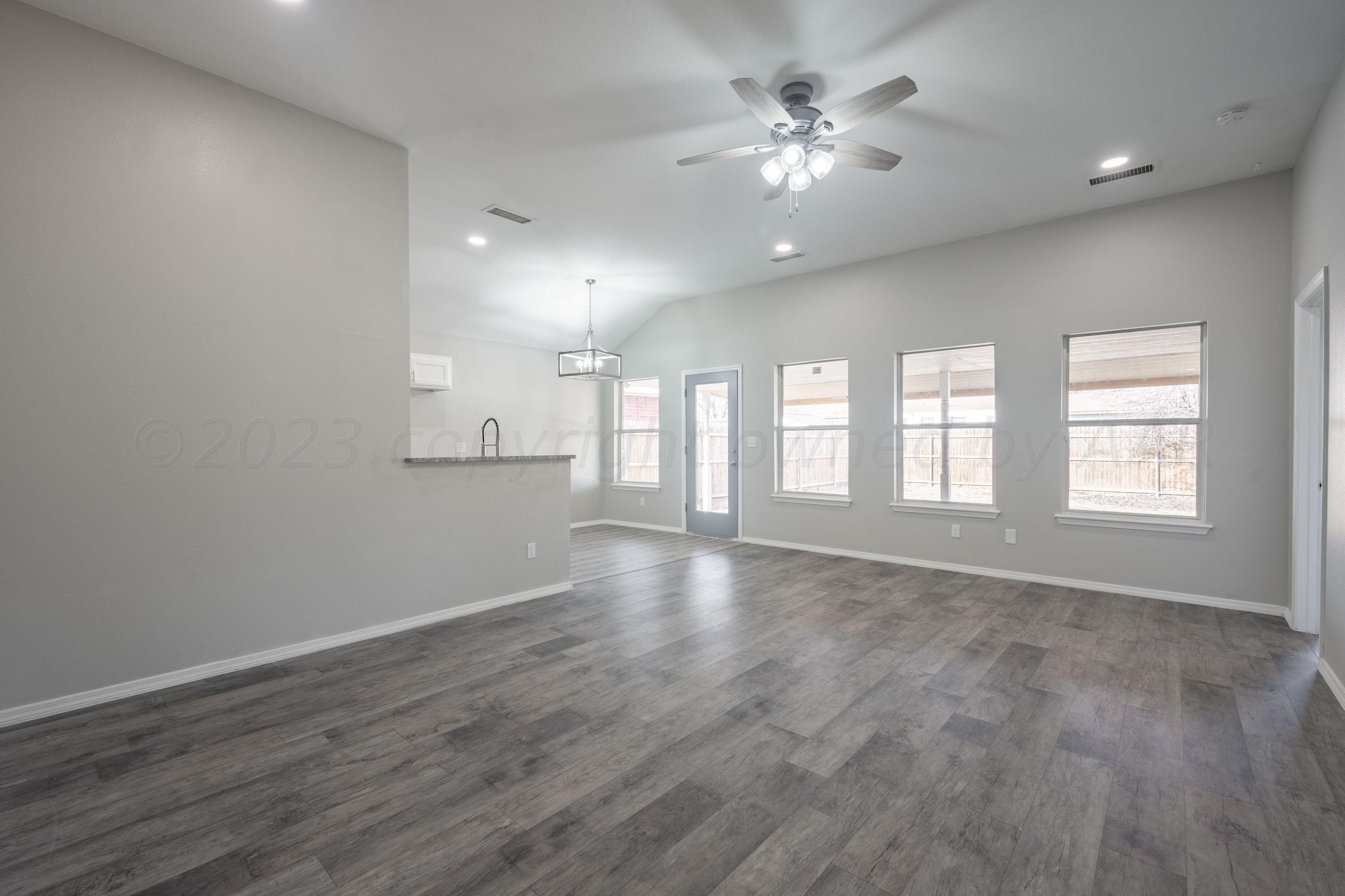 4712 Capulin Lane Amarillo, TX 79110 - Photo 15 of 18 a view of an empty room with chandelier fan and wooden floor