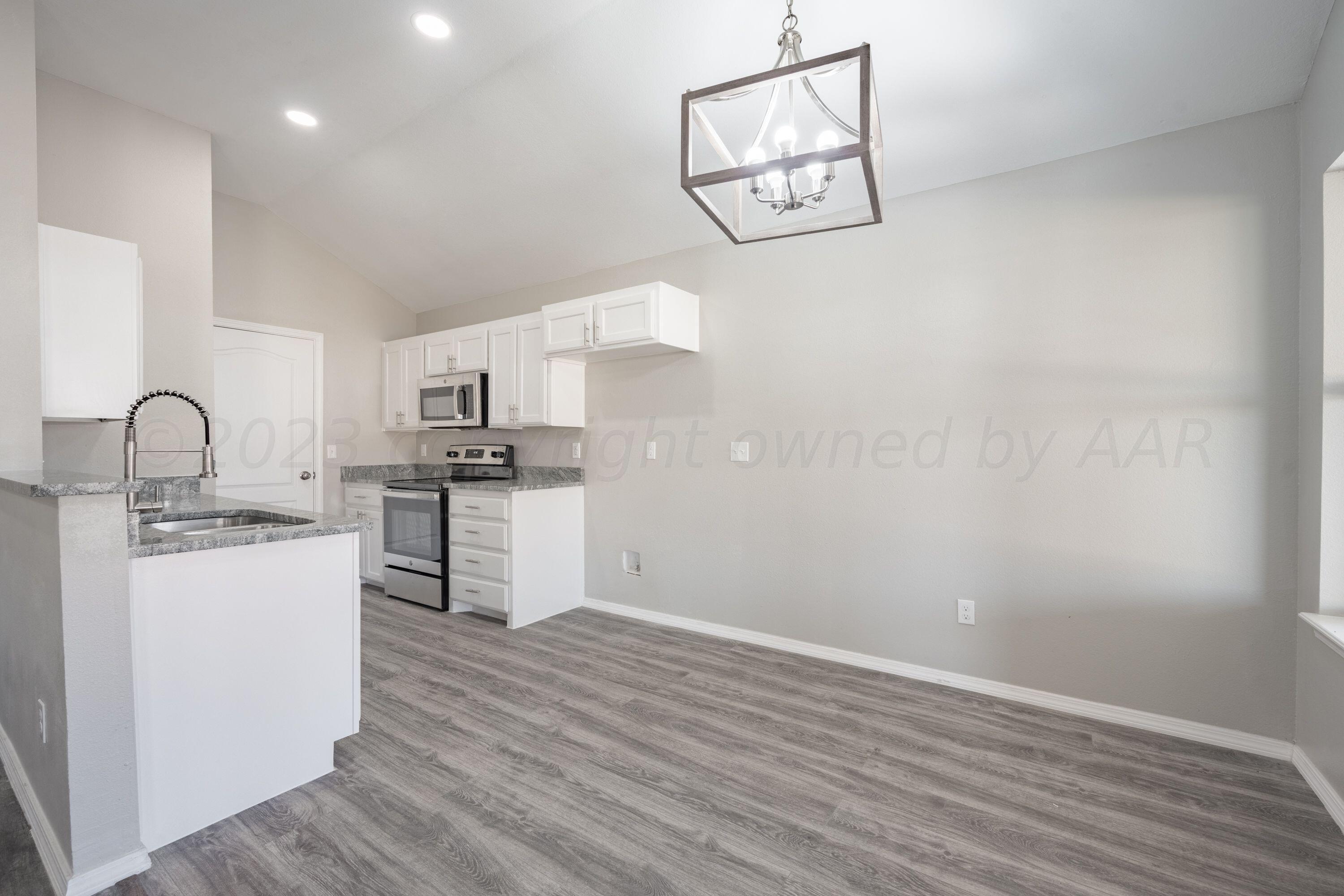 4712 Capulin Lane Amarillo, TX 79110 - Photo 5 of 18 a kitchen with granite countertop white cabinets and stainless steel appliances