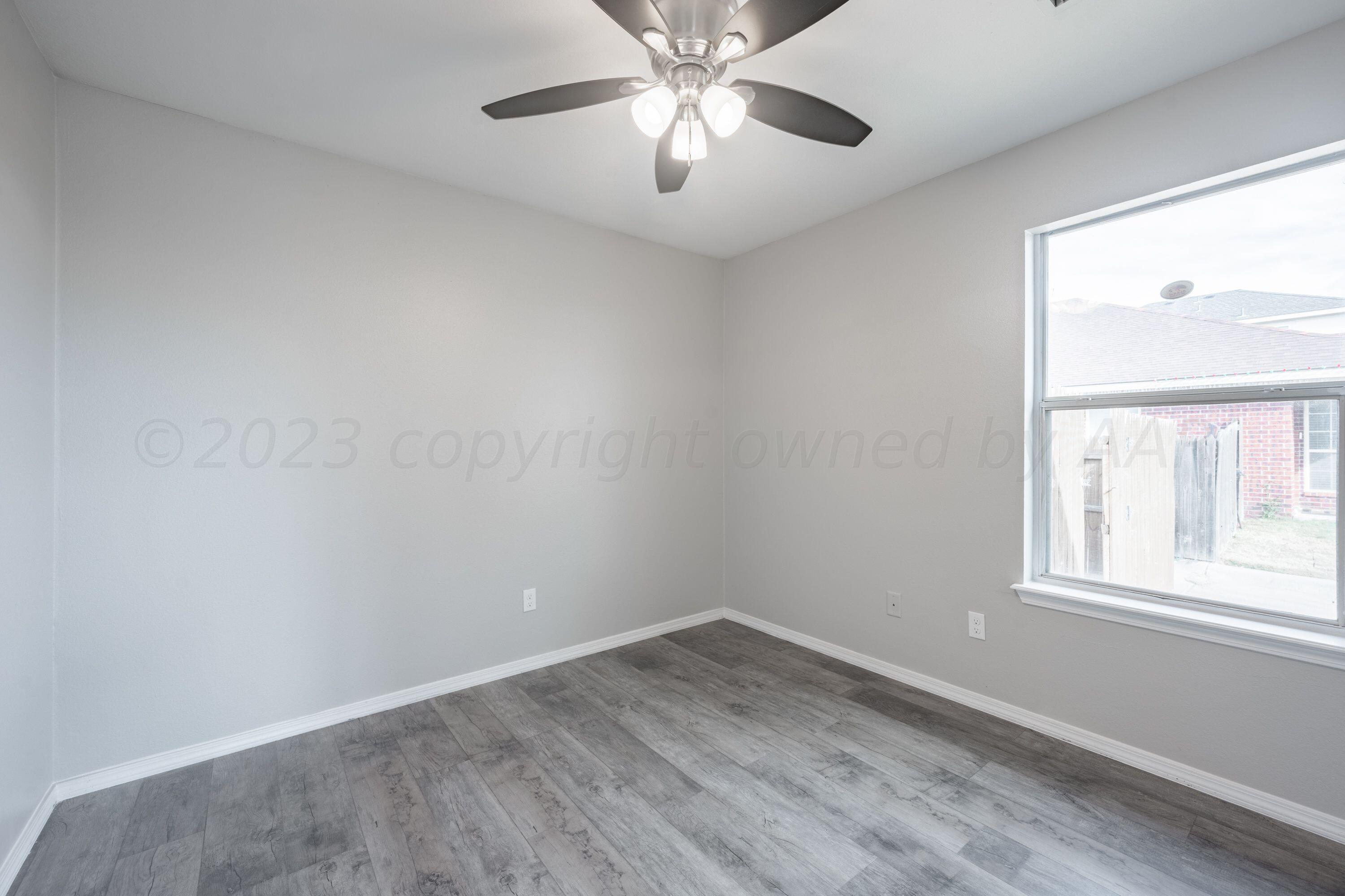 4712 Capulin Lane Amarillo, TX 79110 - Photo 7 of 18 wooden floor in an empty room with a window