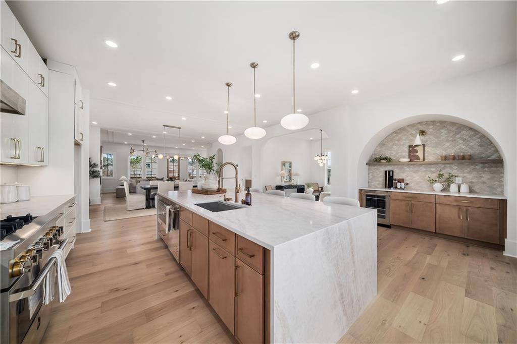245 Lask Lane Milton, GA 30004 - Photo 3 of 87 a large kitchen with kitchen island a stove a sink a refrigerator and a dining table with wooden floor