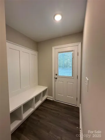 a view of an empty room with wooden floor and window