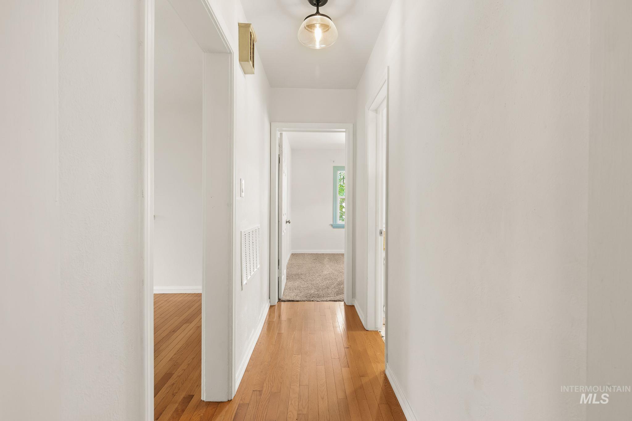 928 3rd Street Clarkston, WA 99403 - Photo 18 of 44 Hallway featuring wood-finish flooring, white walls, and a contemporary ceiling light fixture