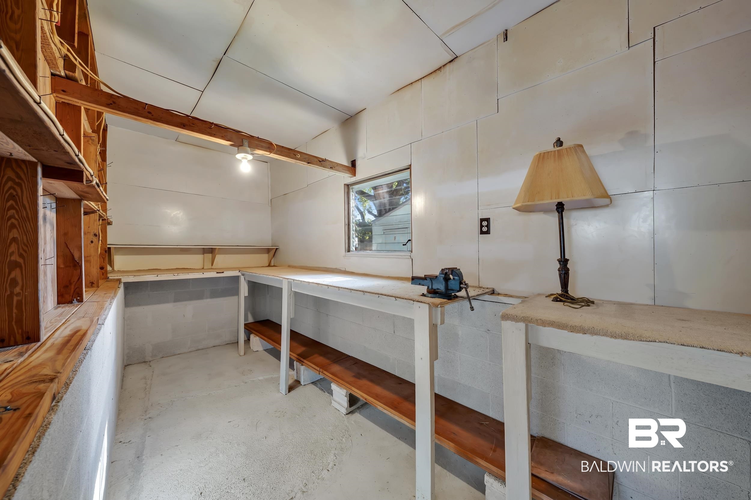 304 West Myrtle Avenue Foley, AL 36535 - Photo 21 of 29 Utility room featuring concrete block walls, a single-pane window, exposed wood framing, built-in wooden shelving, and a concrete floor