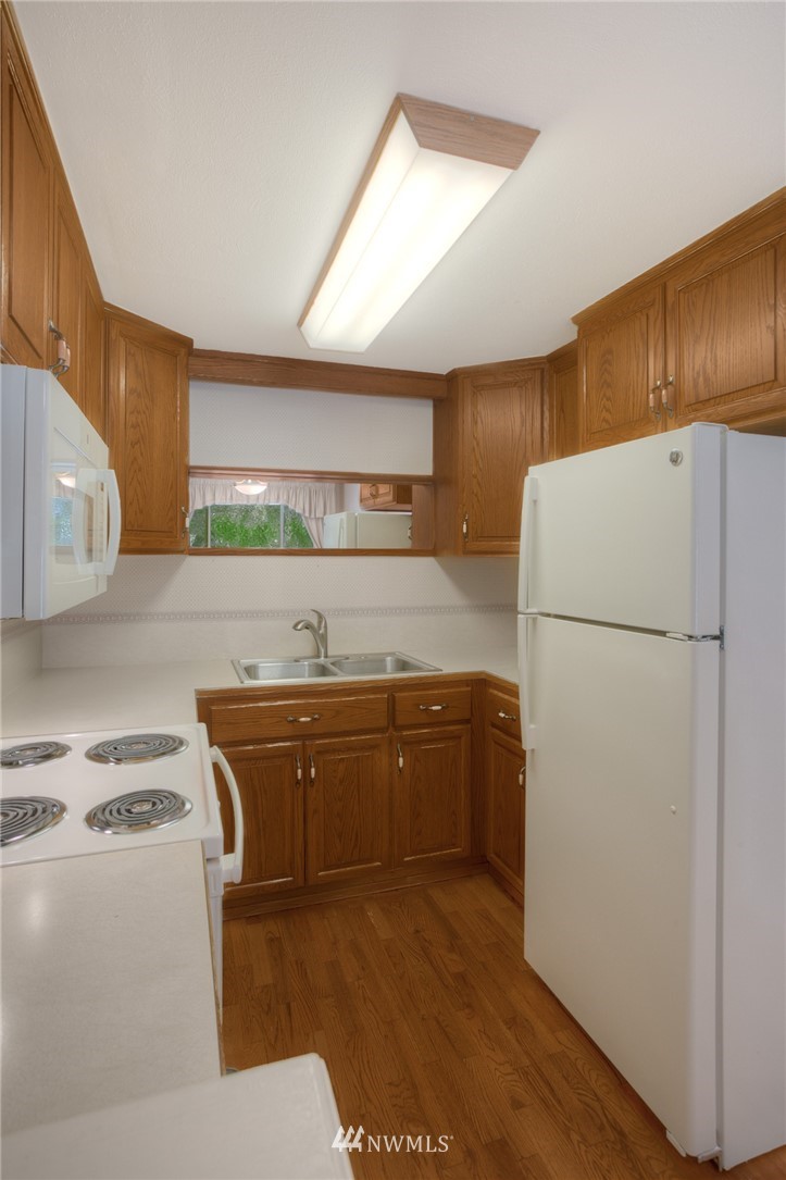 619 Southwest Normandy Road Normandy Park, WA 98166 - Photo 6 of 24 a kitchen with stainless steel appliances granite countertop a refrigerator a stove and a sink with wooden floors