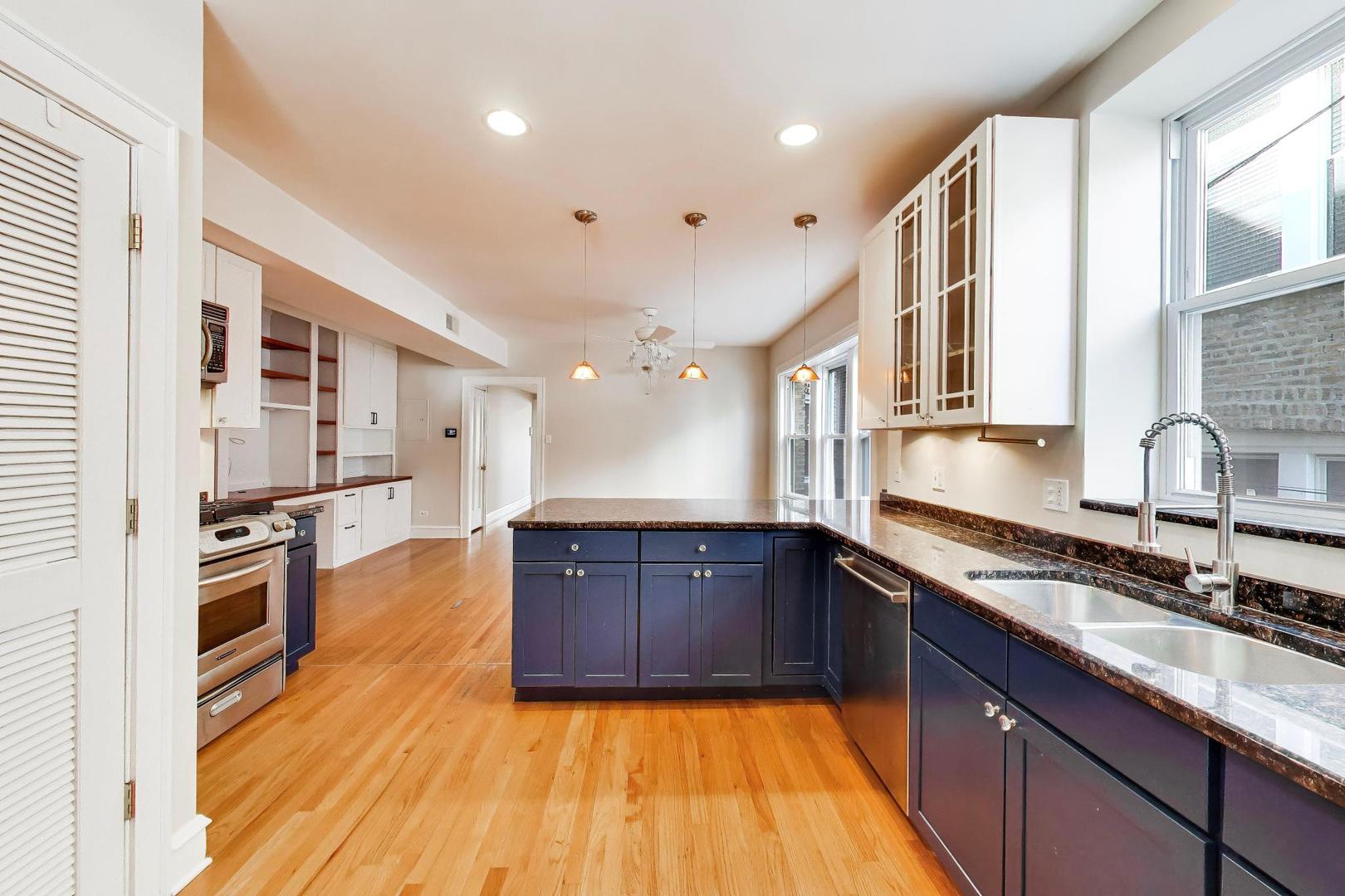 1734 West Foster Avenue, Unit 1 Chicago, IL 60640 - Photo 19 of 24 a large kitchen with stainless steel appliances granite countertop a sink dishwasher stove and oven with wooden floor