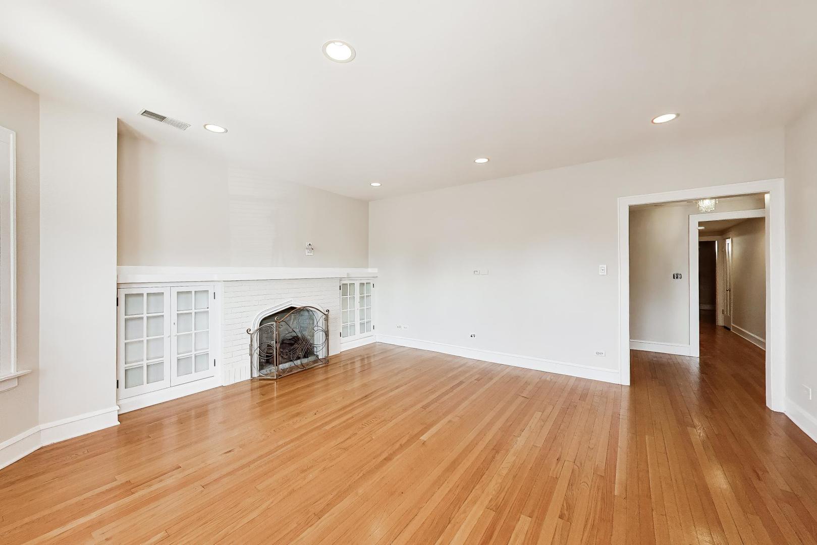 1734 West Foster Avenue, Unit 1 Chicago, IL 60640 - Photo 3 of 24 a view of empty room with wooden floor and fireplace