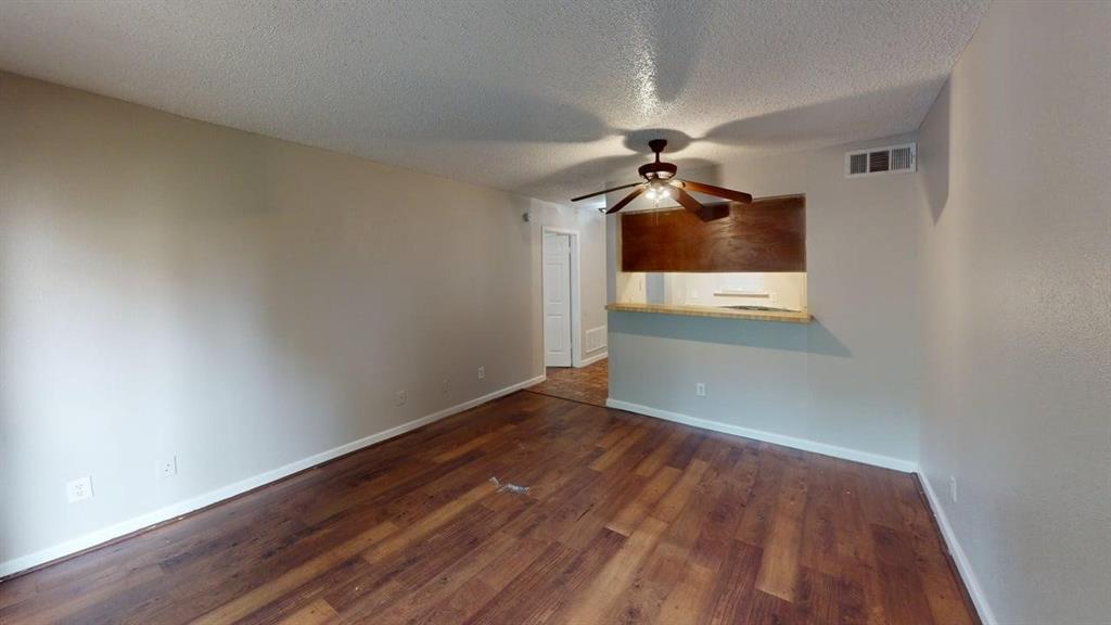 8110 Skillman Street, Unit 1016 Dallas, TX 75231 - Photo 4 of 12 Open-concept living area featuring wood-finish flooring, light neutral walls, and a ceiling fan with integrated lighting