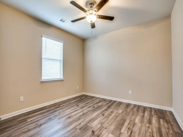 an empty room with a window and a ceiling fan