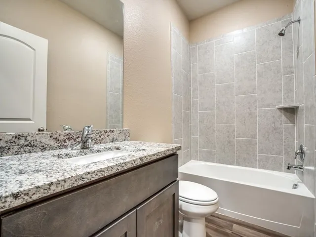 a bathroom with a granite countertop sink a toilet a mirror and bathtub