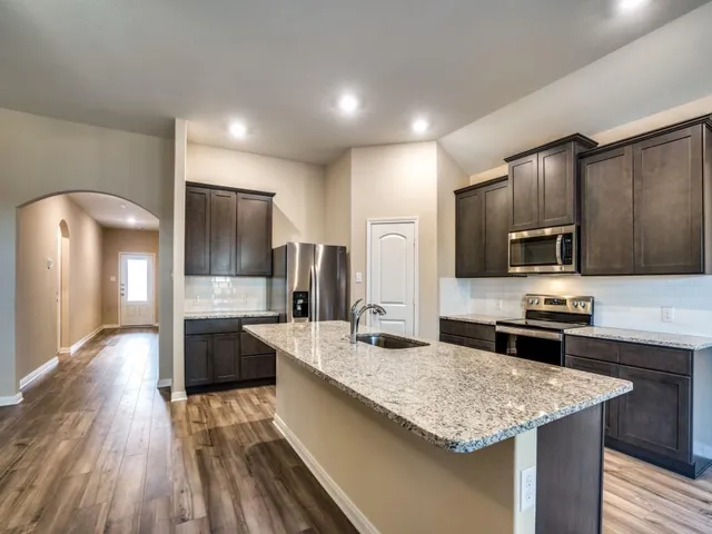 a kitchen with stainless steel appliances granite countertop a sink stove and refrigerator