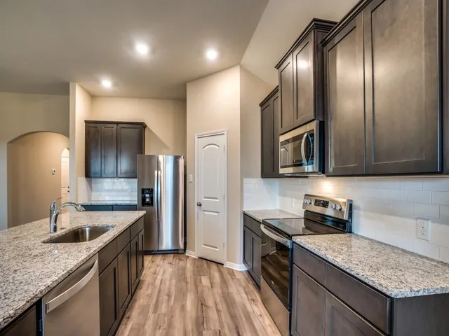 a kitchen with stainless steel appliances granite countertop a sink a stove and refrigerator