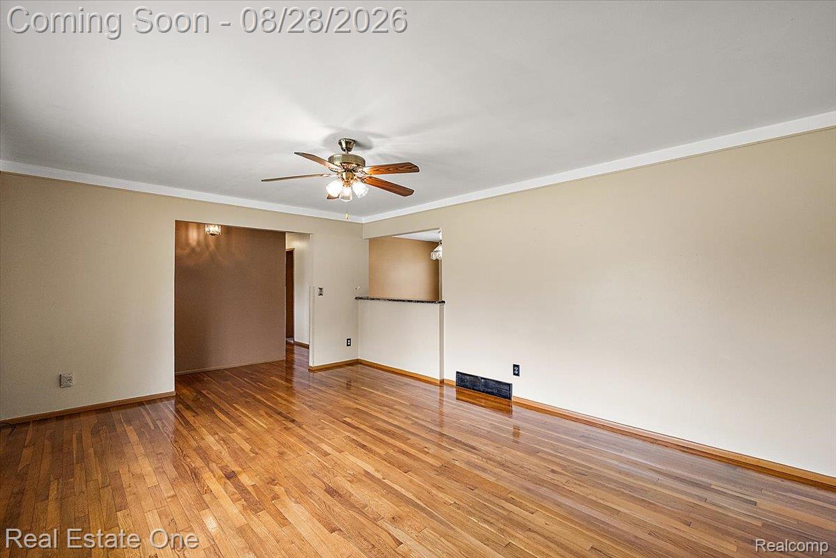 15250 34 Mile Road Armada, MI 48005 - Photo 23 of 49 Hardwood flooring throughout, crown molding, ceiling fan with integrated lighting, and a partial wall with a stone-finish countertop