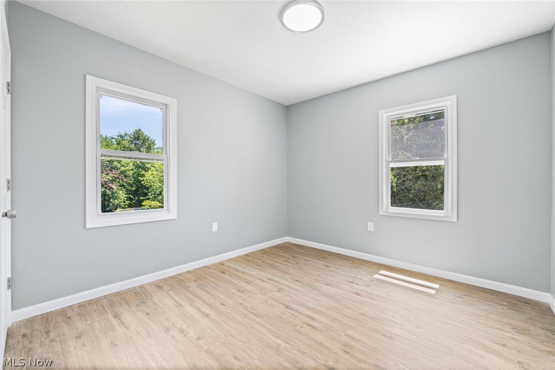 3925 Riverside Avenue Cleveland, OH 44109 - Photo 30 of 48 Light gray painted walls, wood-finish flooring, two windows, white trim, and a ceiling-mounted light fixture