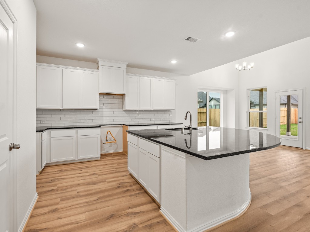 306 Strm Bnd Way Rosenberg, TX 77471 - Photo 9 of 35 a kitchen with kitchen island granite countertop a sink and white cabinets with wooden floor