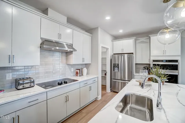 a kitchen with stainless steel appliances granite countertop a sink a stove and a refrigerator