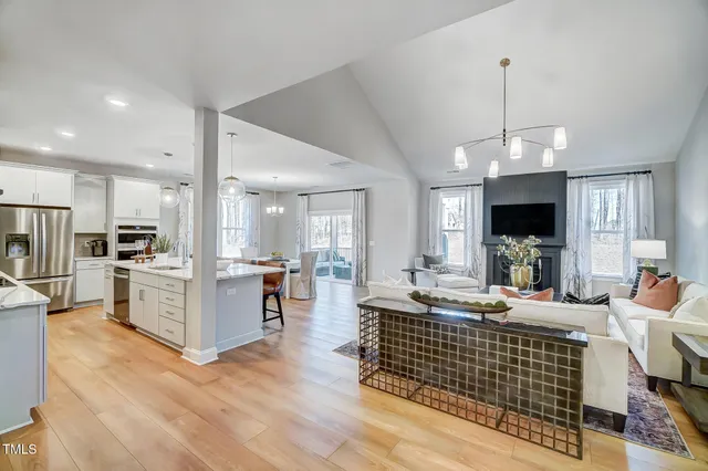 a living room with stainless steel appliances kitchen island granite countertop furniture a fireplace a flat screen tv and a kitchen view