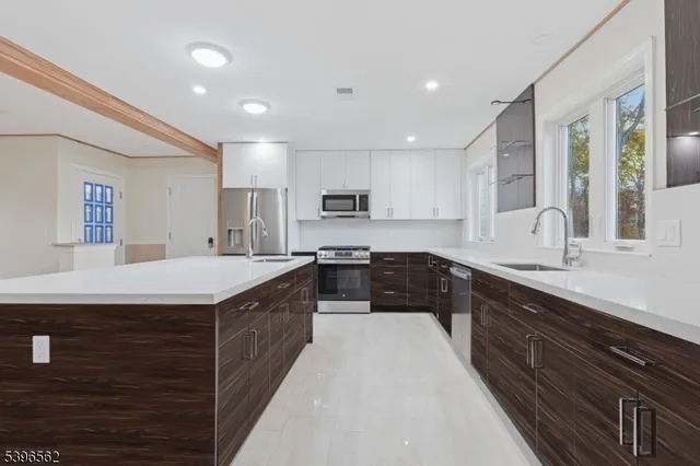 a large kitchen with a large counter top space a sink stainless steel appliances and cabinets