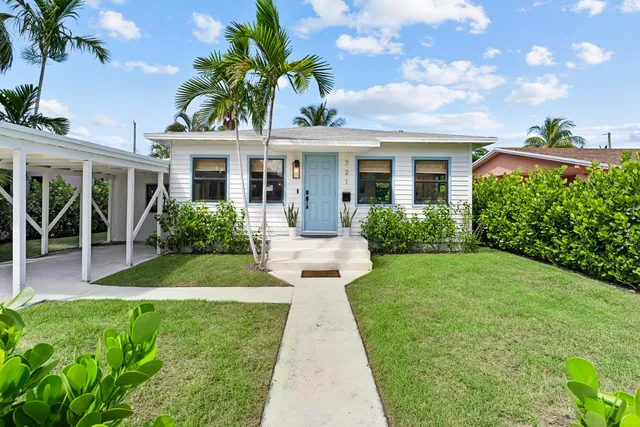 a front view of a house with a yard and potted plants