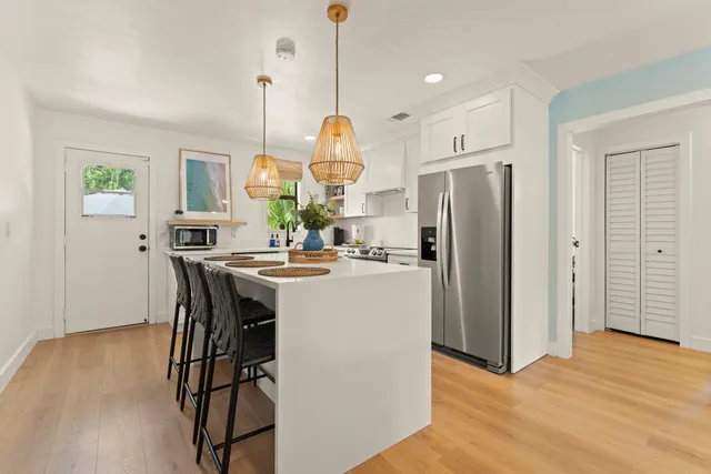 a kitchen with stainless steel appliances granite countertop a refrigerator a sink dishwasher a stove and a dining table with wooden floor