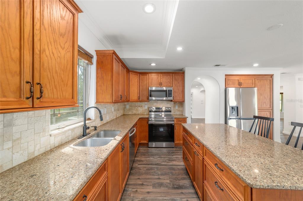 5721 Southwest 31st Street Ocala, FL 34474 - Photo 20 of 41 a large kitchen with kitchen island a large counter top space a sink a window and stainless steel appliances
