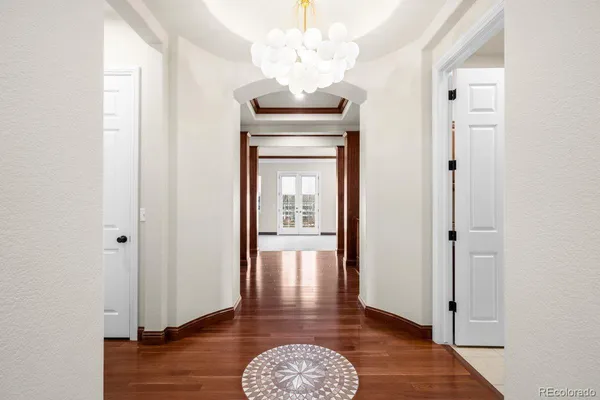 a view of a hallway with wooden floor and a chandelier