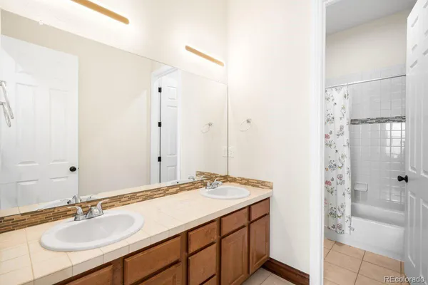 a bathroom with a sink double vanity granite tub shower and a mirror