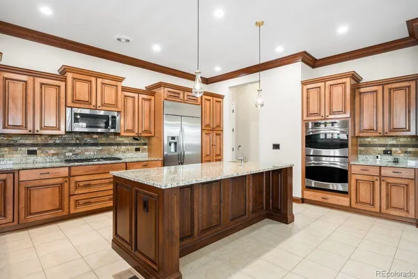 a kitchen with stainless steel appliances granite countertop a stove top oven a sink dishwasher and a refrigerator with wooden cabinets