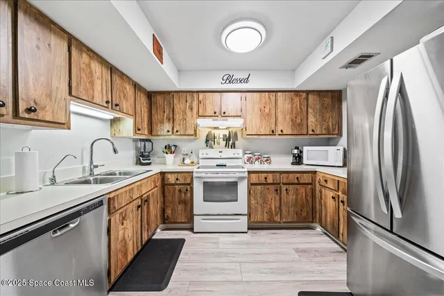 a kitchen with stainless steel appliances granite countertop a sink stove refrigerator and cabinets