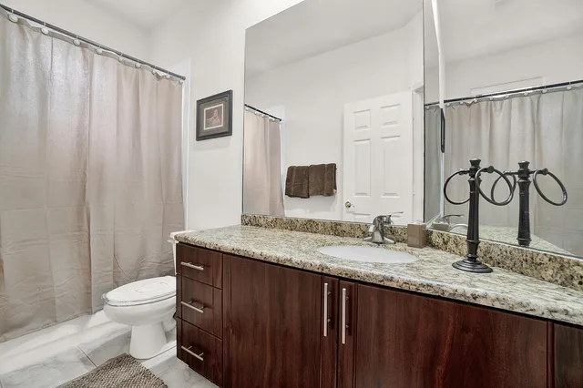 a bathroom with a granite countertop sink toilet and a mirror