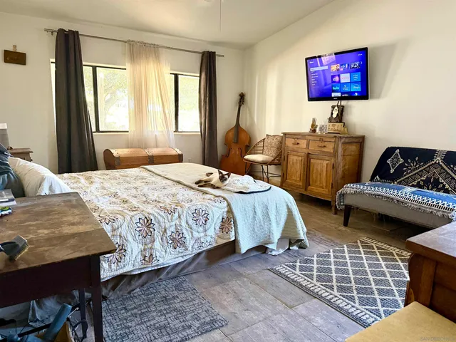 a bedroom with a bed and dresser next to a window