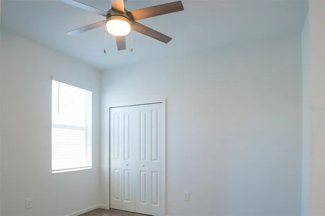 an empty room with a window and a fan