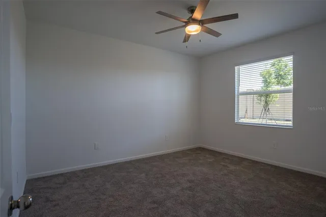 an empty room with a window and a fan