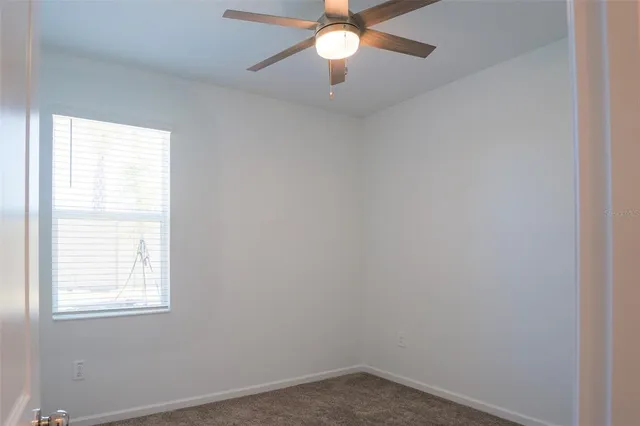 an empty room with a window and a fan