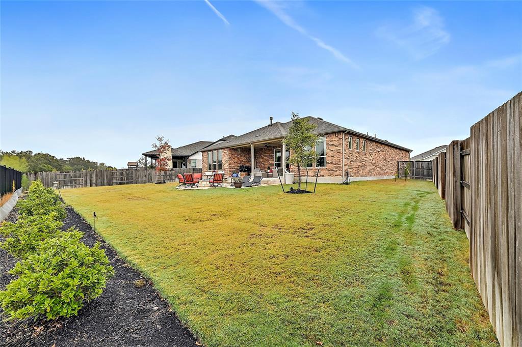 170 Climbing Rock Loop Dripping Springs, TX 78620 - Photo 22 of 30 A spacious backyard with a manicured lawn, complete with a brick-clad home and outdoor living area.
