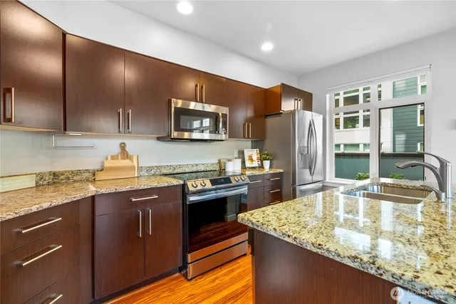 a kitchen with stainless steel appliances granite countertop a sink a stove and a refrigerator