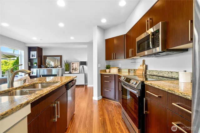 a kitchen with stainless steel appliances granite countertop a stove a sink and a microwave
