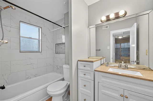 a bathroom with a granite countertop sink a toilet and shower