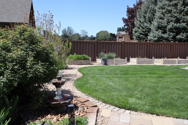 1055 North 1000 East Mapleton, UT 84664 - Photo 87 of 112 Expansive lawn area featuring a stone water fountain, gravel pathway, mature evergreen trees, and raised garden beds