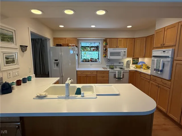 a large kitchen with stainless steel appliances a large counter top a stove and a refrigerator