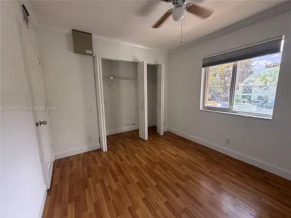 a view of an empty room with wooden floor and a window