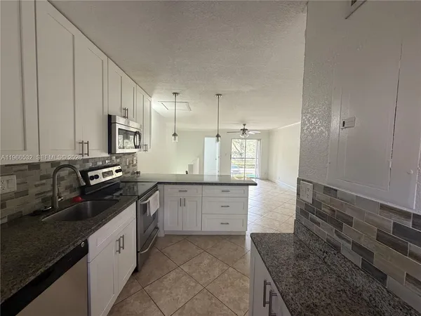 a kitchen with granite countertop white cabinets and white appliances