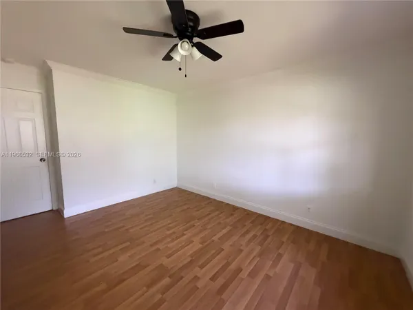 an empty room with wooden floor fan and windows