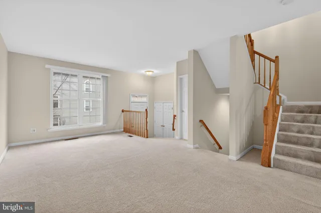 a view of an empty room with stairs and a window