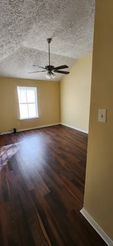 a view of empty room with window and wooden floor