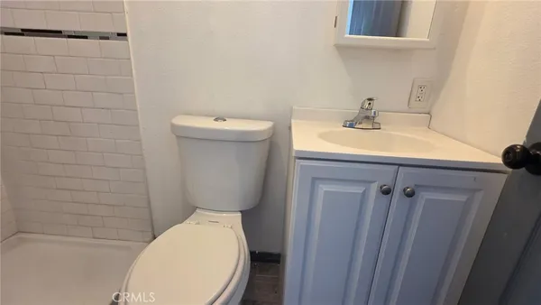 a bathroom with a toilet a sink and wooden floor