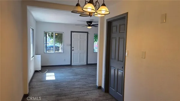 a view of a hallway with wooden floor and a chandelier